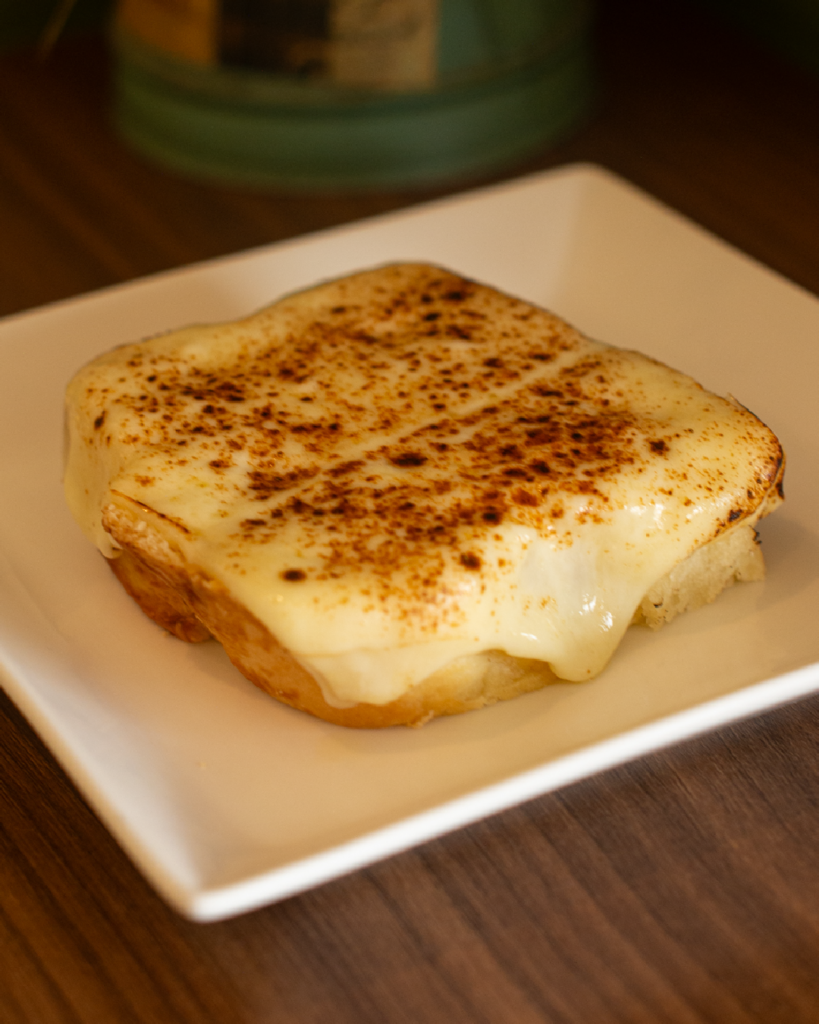 Pão com presunto e queijo derretido, servido bem quentinho.